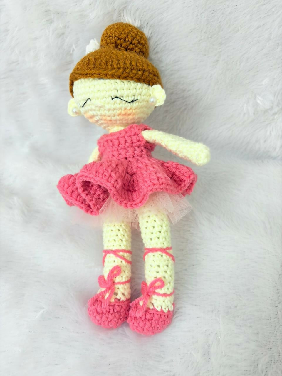 Crocheted doll with a pink dress, yellow shoes, and brown hat on a white background
