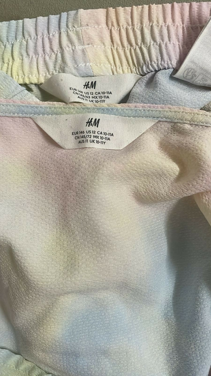 Close-up of an H&M label on a garment with a pastel tie-dye pattern.