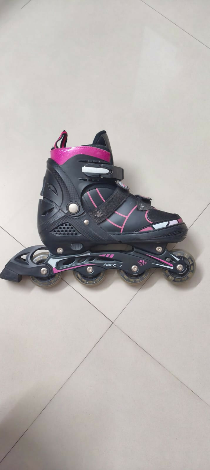 Black and pink inline skate on a light gray floor
