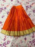 Orange skirt with gold hem on a floral-patterned fabric background