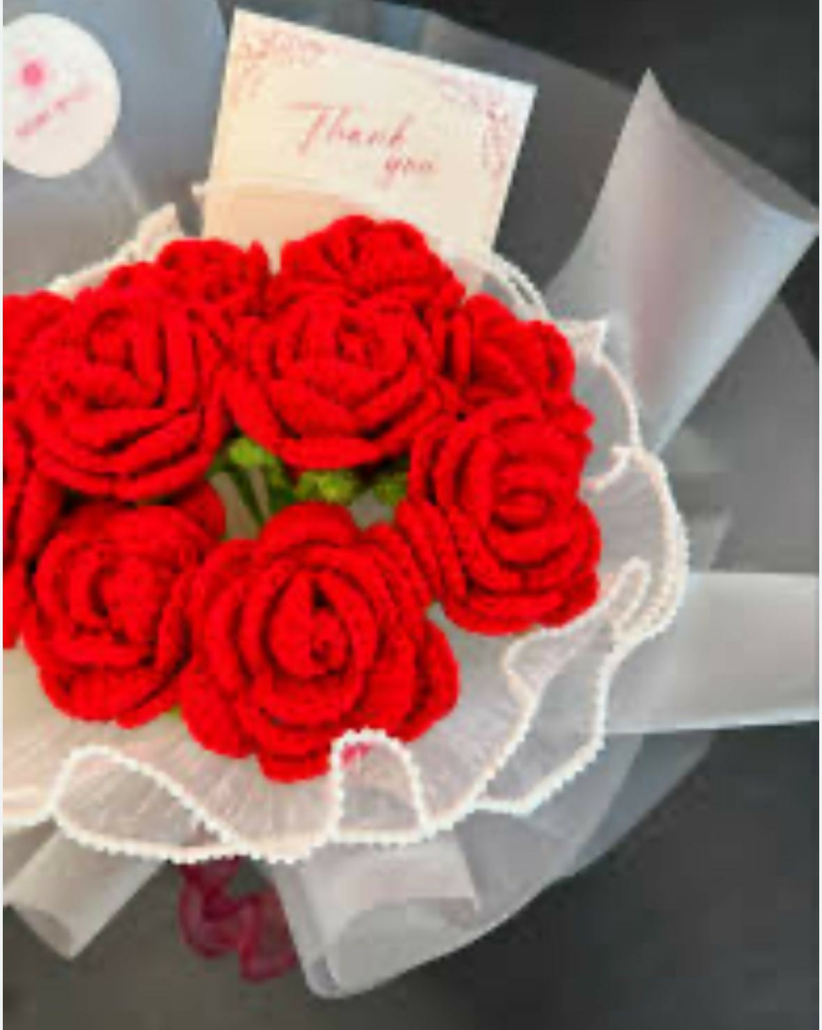 Bouquet of red roses with a 'Thank you' card on a gray surface