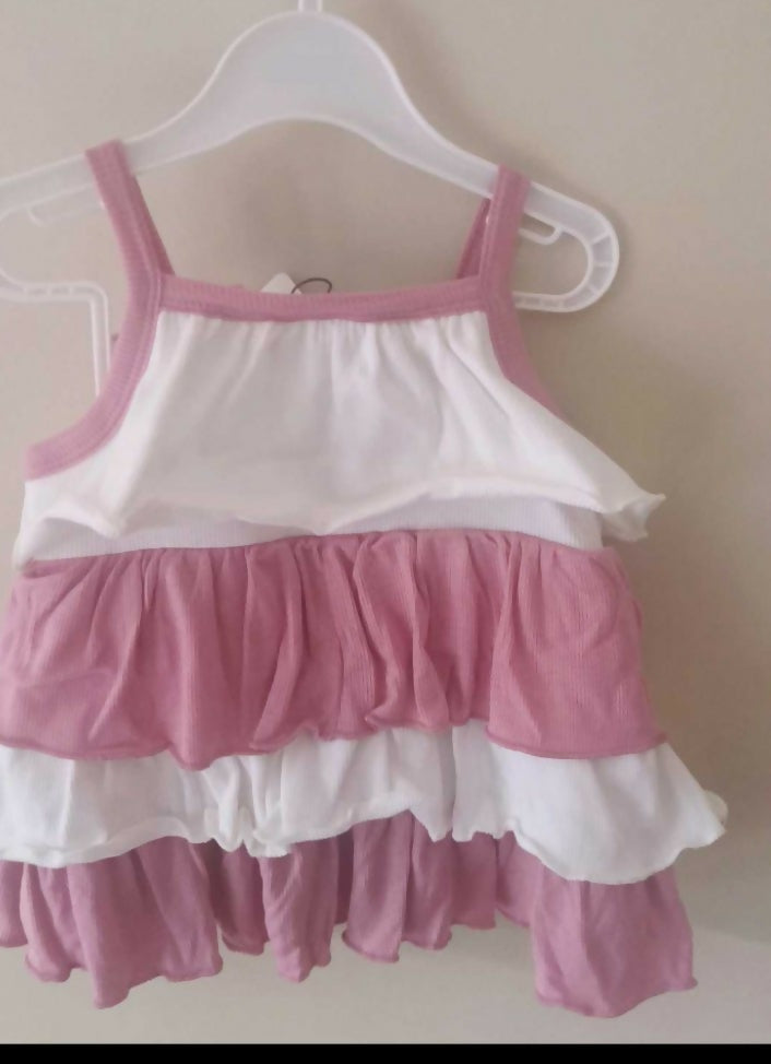 Pink and white dress on a hanger against a beige wall