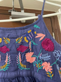 Blue dress with colorful floral embroidery hanging on a rack.