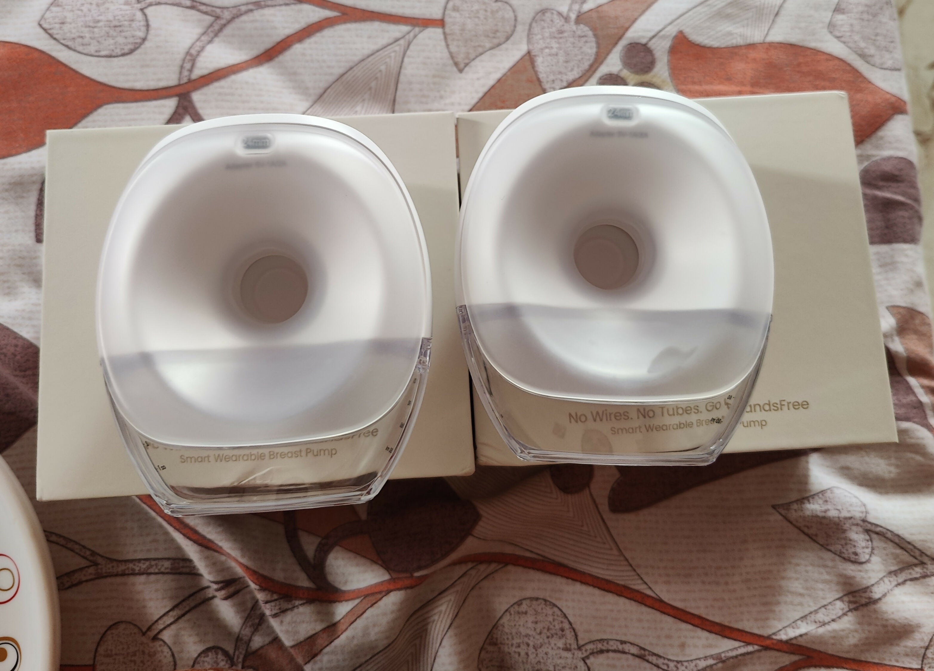 Two white containers with lids on a patterned surface