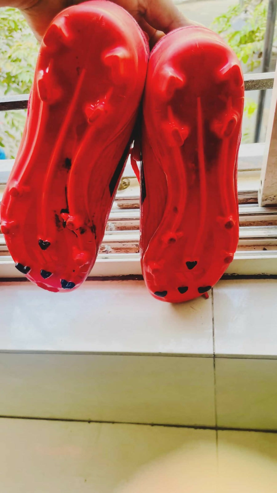 Red sandals with black heart patterns on a light-colored floor.