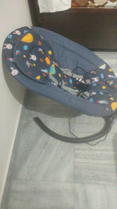 Baby swing with colorful patterns on a wooden floor