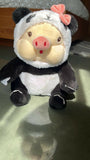 Plush toy resembling a panda with a pig's snout on a reflective surface.