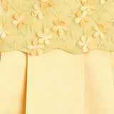 Close-up of yellow fabric with floral embroidery on a matching yellow background