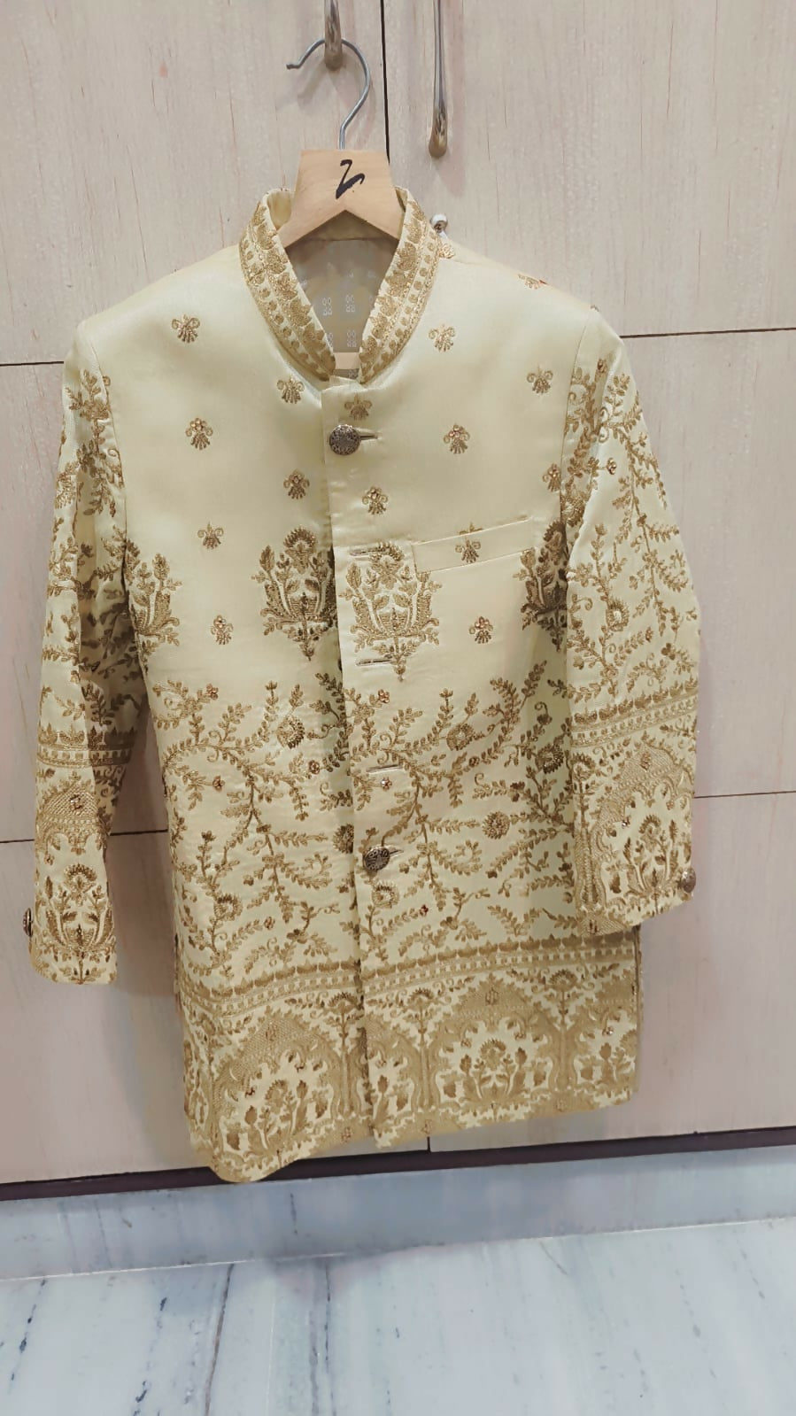 Embroidered traditional outfit on a hanger against a light background