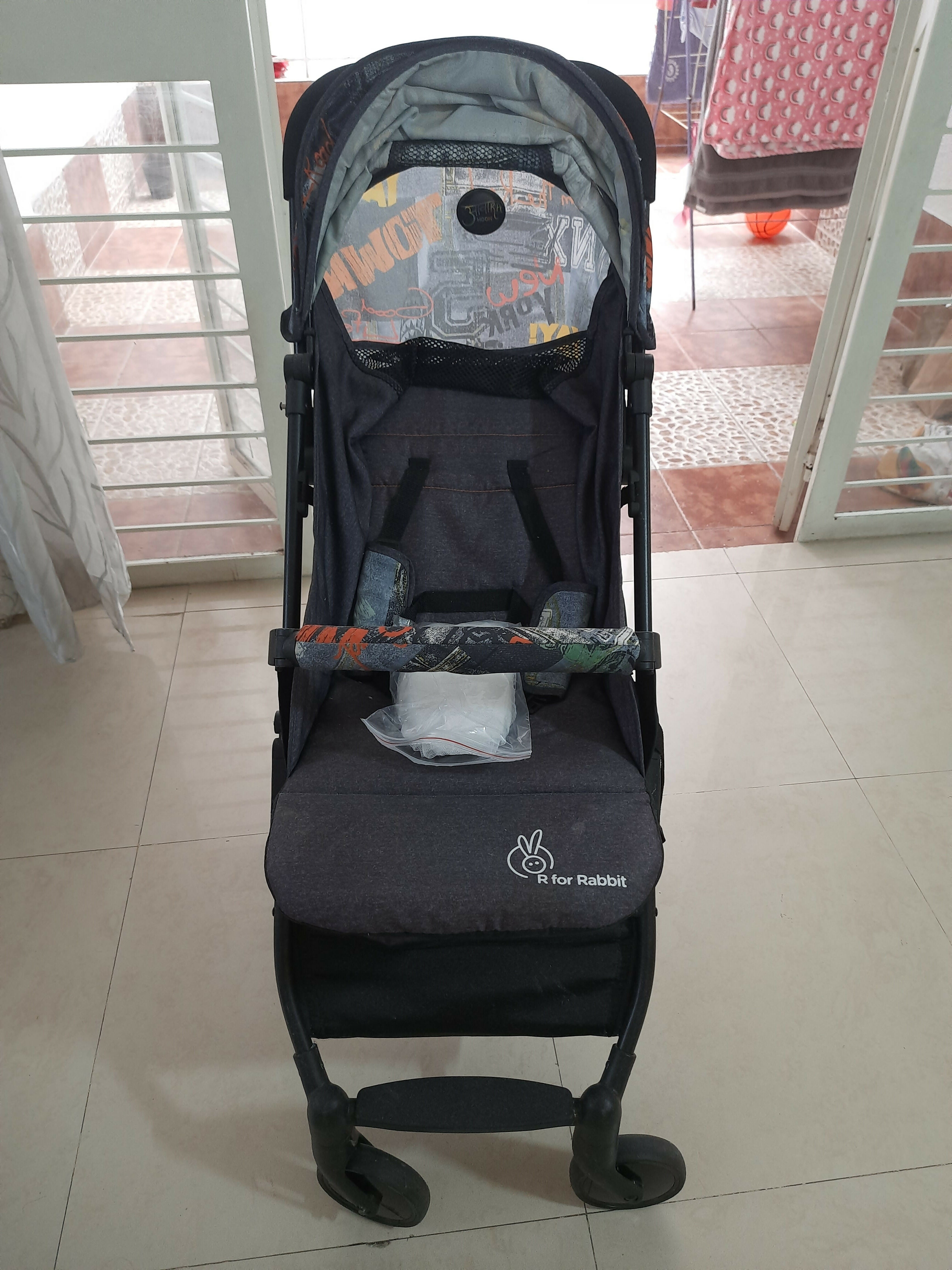 Black stroller with a visible brand logo on a tiled floor.