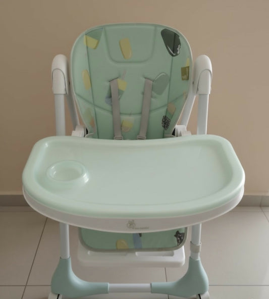 Green and white high chair with butterfly design on a beige background