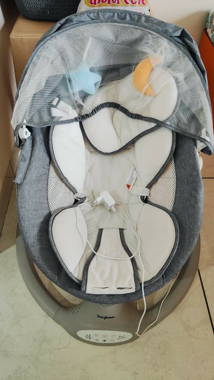 BAYBEE electric baby swing with gentle rocking motion, cushioned seat, secure safety harness, soothing comfort, and relaxing support for babies during rest and play.