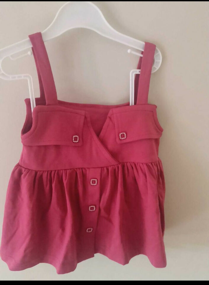 Pink dress with straps on a white hanger against a beige wall