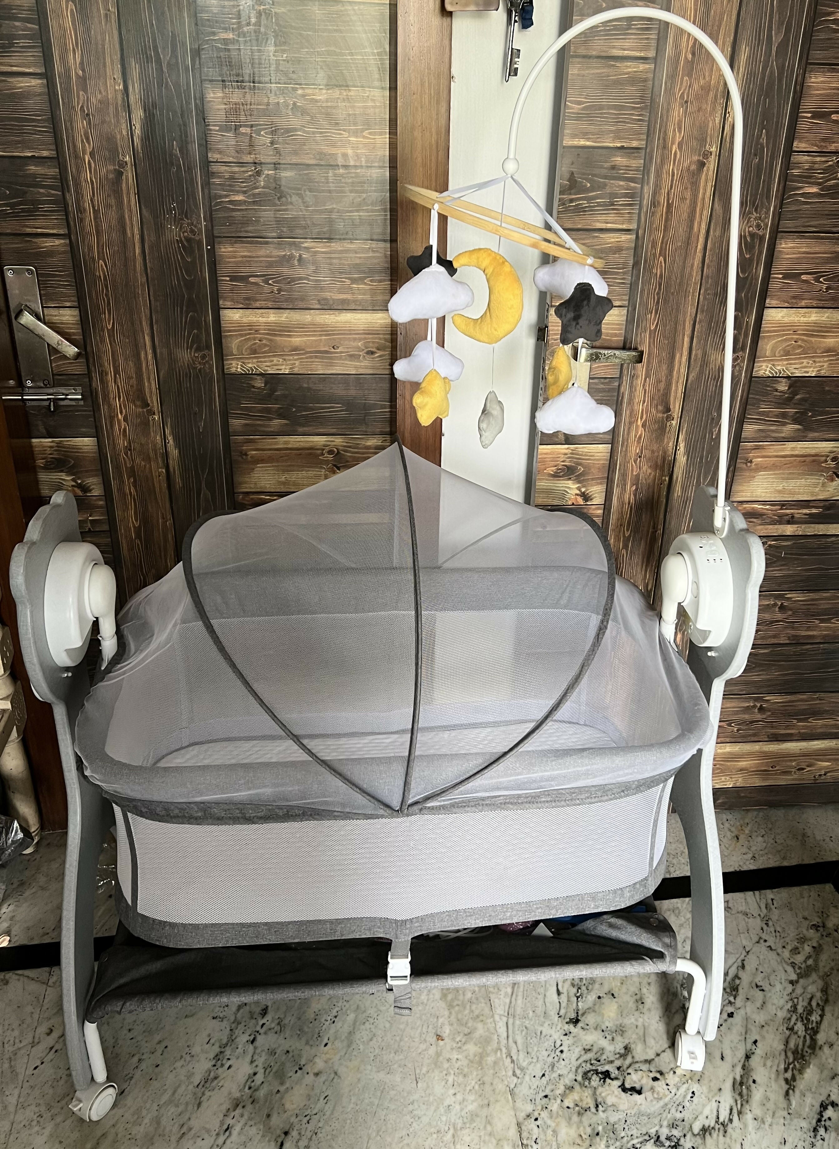 MEE MEE Swing Cradle for Baby featuring a mosquito net, comfortable mattress pad, gentle swinging design and wheels with locking function for convenient movement and supervised resting at home.