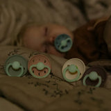 Set of colorful baby pacifiers on a soft surface with a blurred background