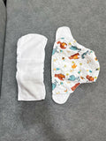 Two baby diapers on a gray surface, one plain and one with colorful designs.