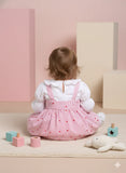 Child wearing a pink dress with white ruffled shirt