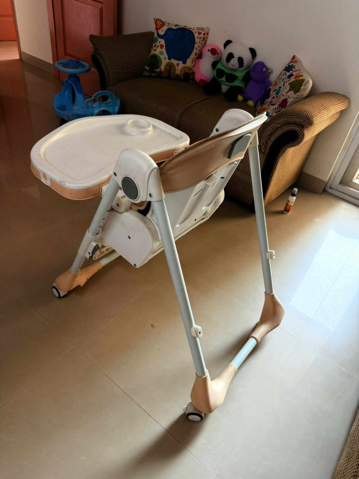 Baby high chair in a room with a couch and toys