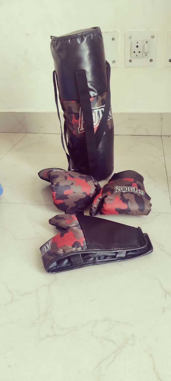 Camouflage-patterned boxing gloves and punching bag on a tiled floor.