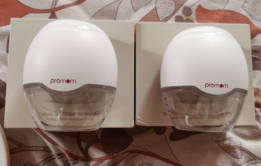 Two Promom breast pumps on a floral-patterned surface