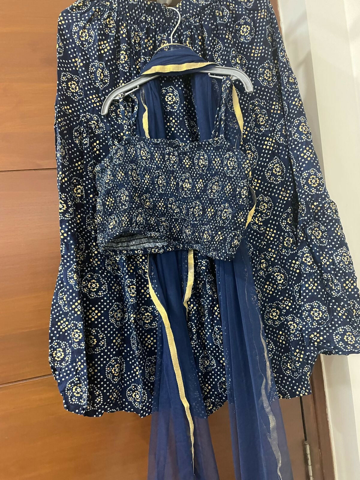 Blue floral-patterned outfit with a top and skirt on a hanger against a wooden background