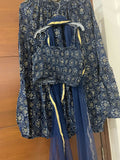 Blue floral-patterned outfit with a top and skirt on a hanger against a wooden background