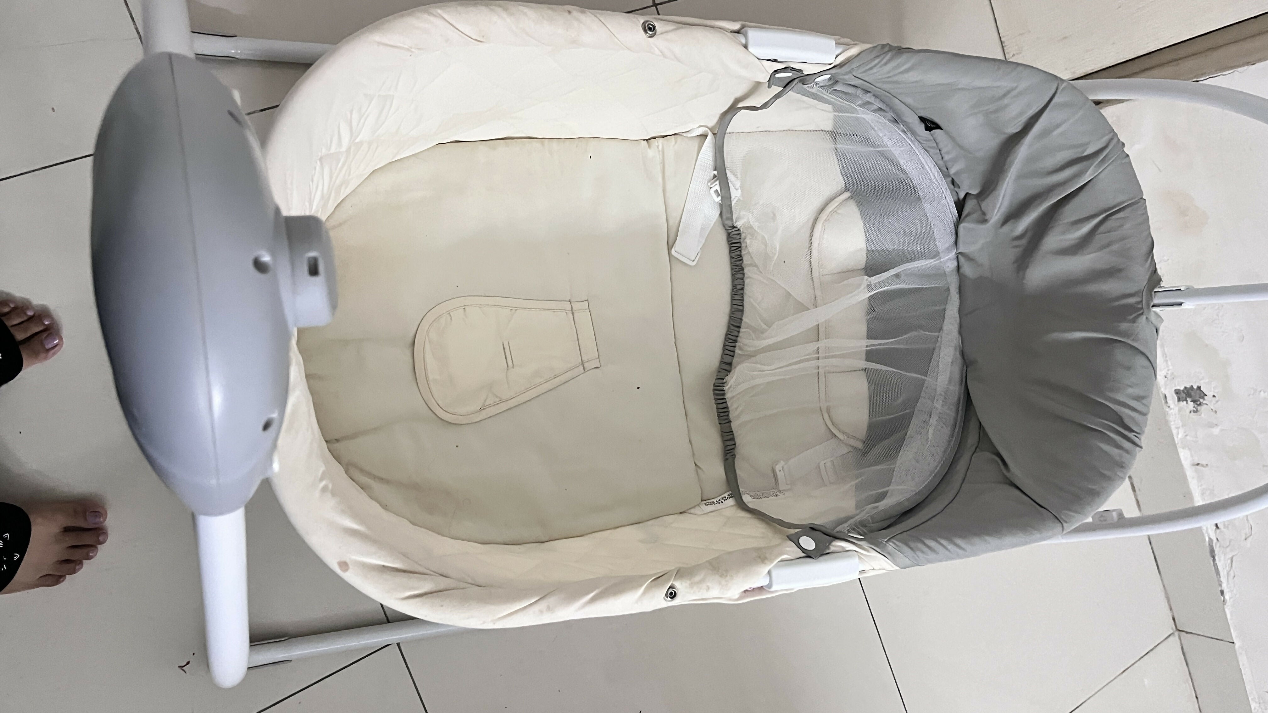 Baby swing with a baby seat on a tiled floor