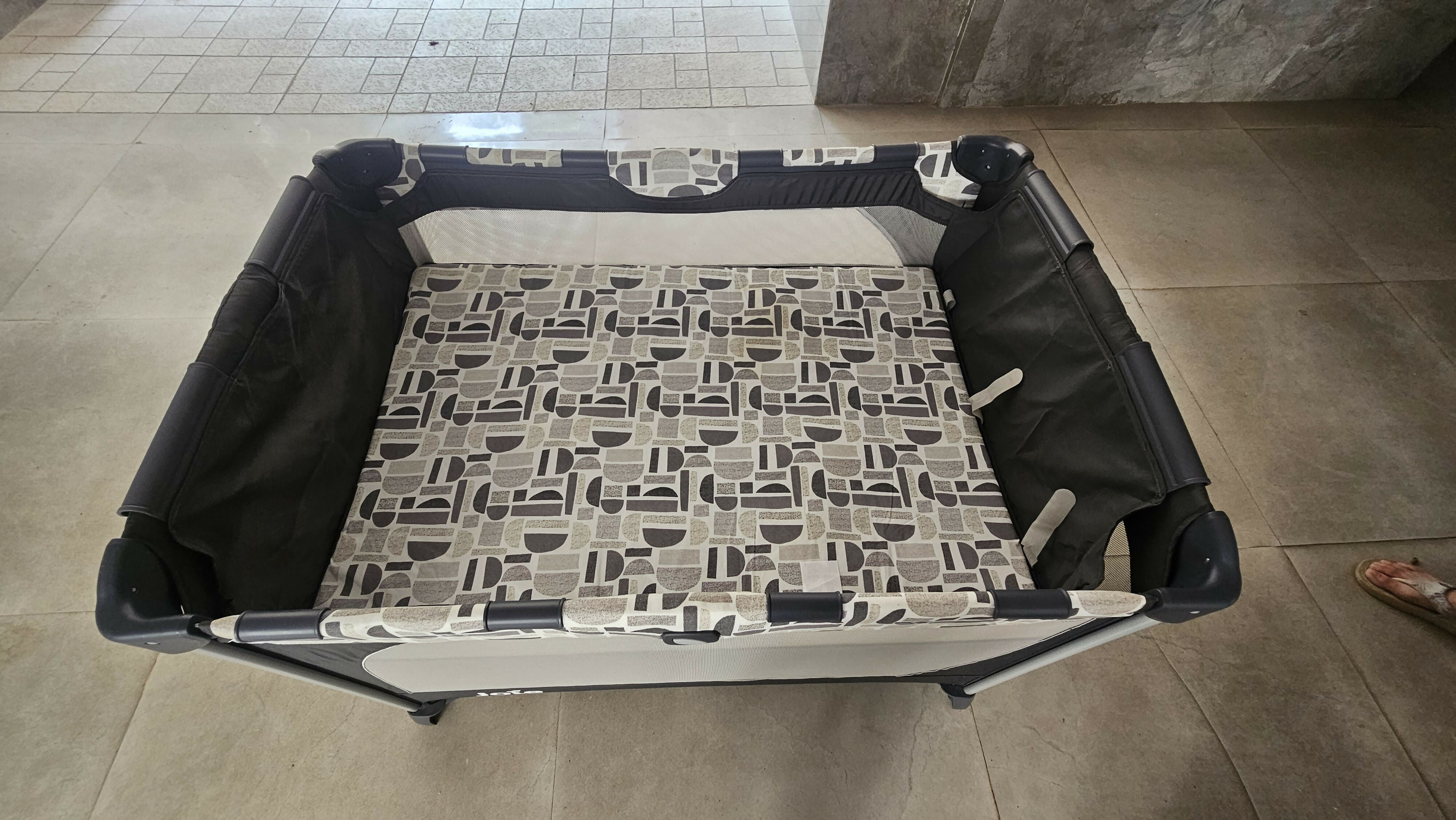 Joie Commuter Change playpen cot with changing station, secure play area, foldable design, mesh sides, and comfortable space for baby sleep, play, and diaper changes.