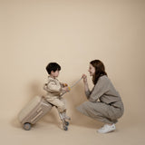 Woman and child playing with a suitcase against a beige background