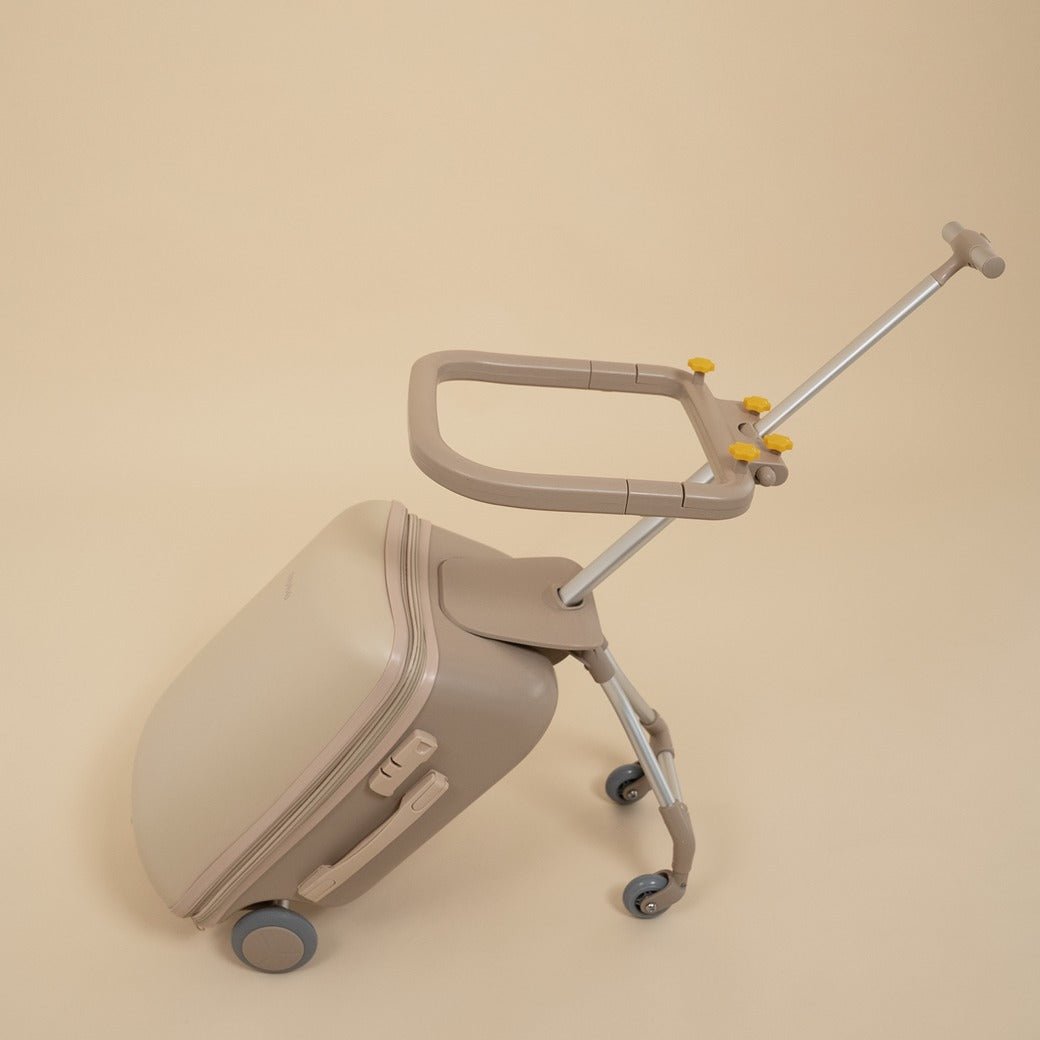 Beige suitcase with a rolling handle on a beige background