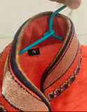 Close-up of a red hat with decorative elements and a blue ribbon on a blurred background
