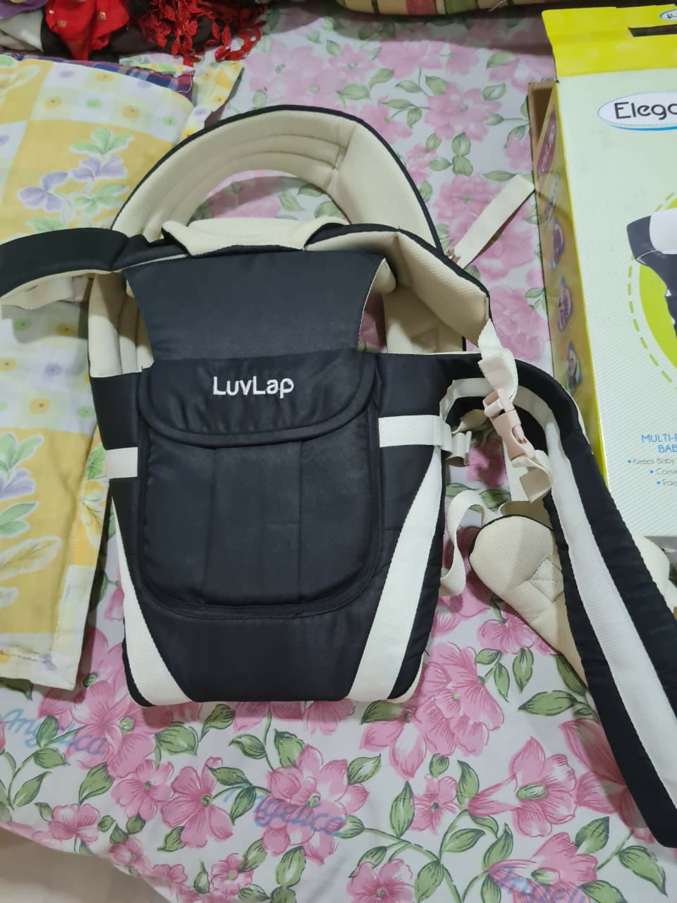 Black baby carrier with 'Luvlap' branding on a floral surface