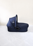 babycab Noah Carrycot Bassinet in Navy Blue, designed as a stroller attachment with a comfortable padded interior, protective canopy, sturdy construction, and cozy lie-flat space for newborns and young infants.