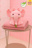 Pink elephant-shaped pillow and blanket on a small round table with a pink tiled wall background.