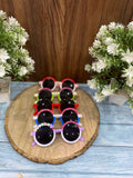 Set of colorful children's sunglasses on a wooden board with flowers on either side.