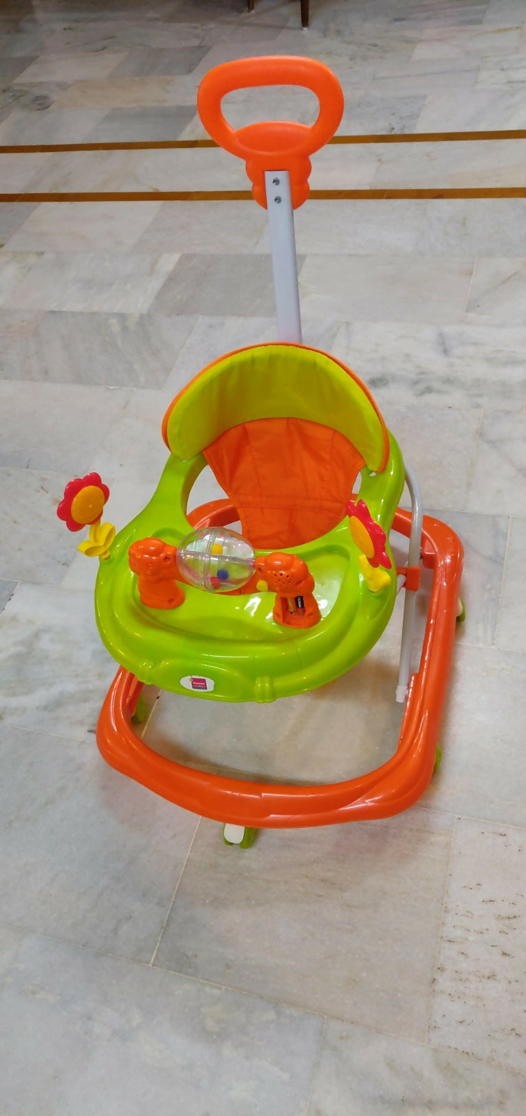 Children's walker with orange and green colors on a tiled floor