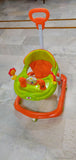 Children's walker with orange and green colors on a tiled floor