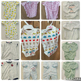 Collage of various baby onesies and clothing items on a wooden surface.