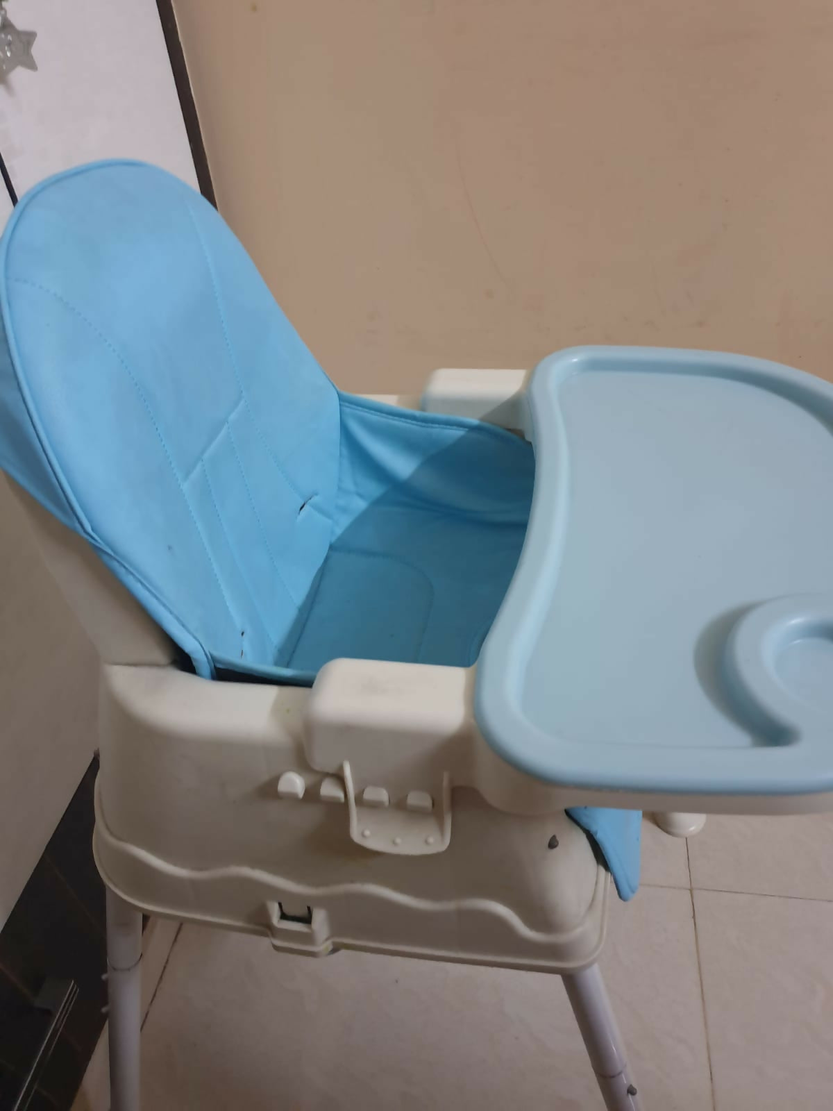 Blue and beige baby high chair with tray on a plain background