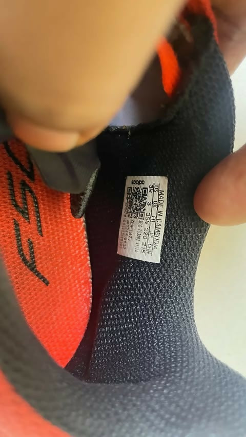 Close-up of a shoe label with a QR code on a black and orange shoe.