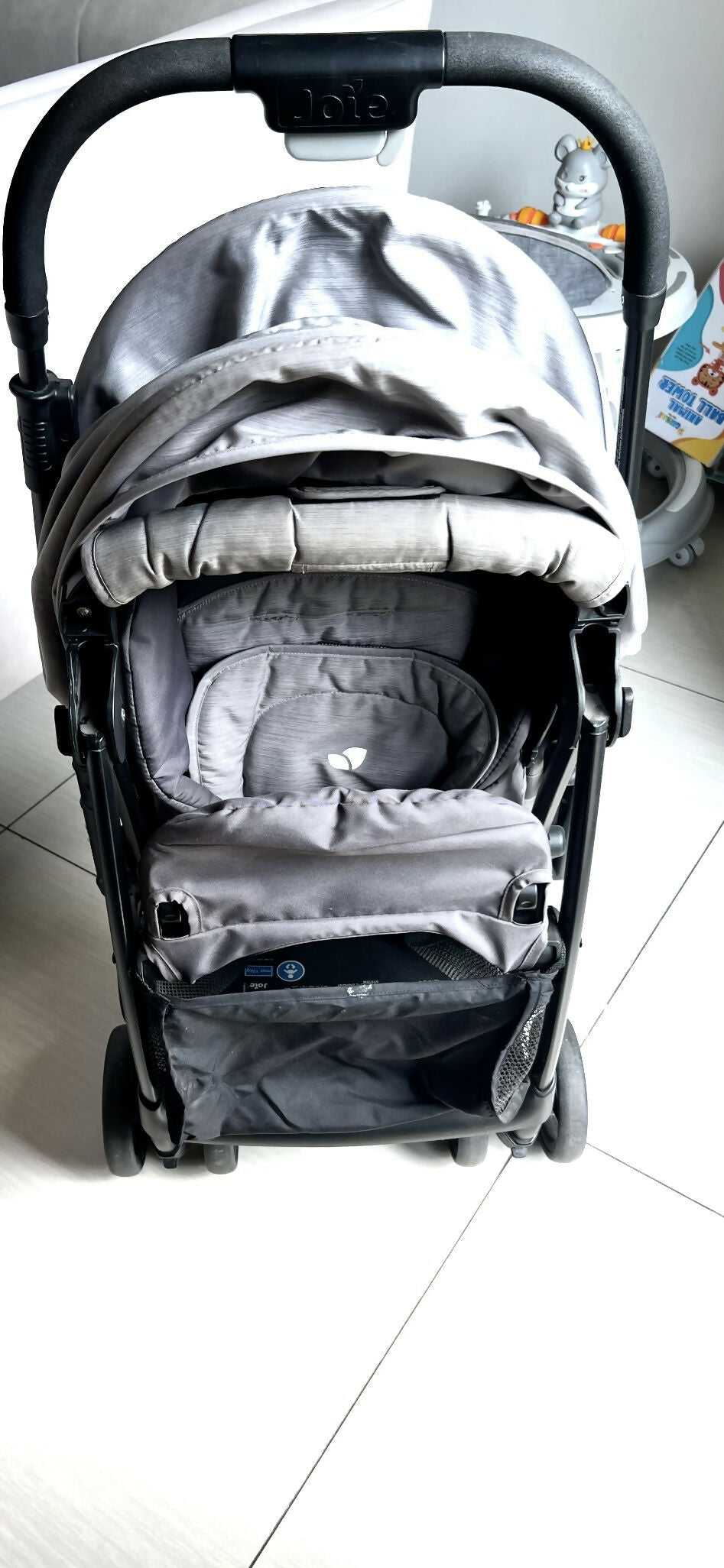 Gray baby stroller on a white floor with a blurred background