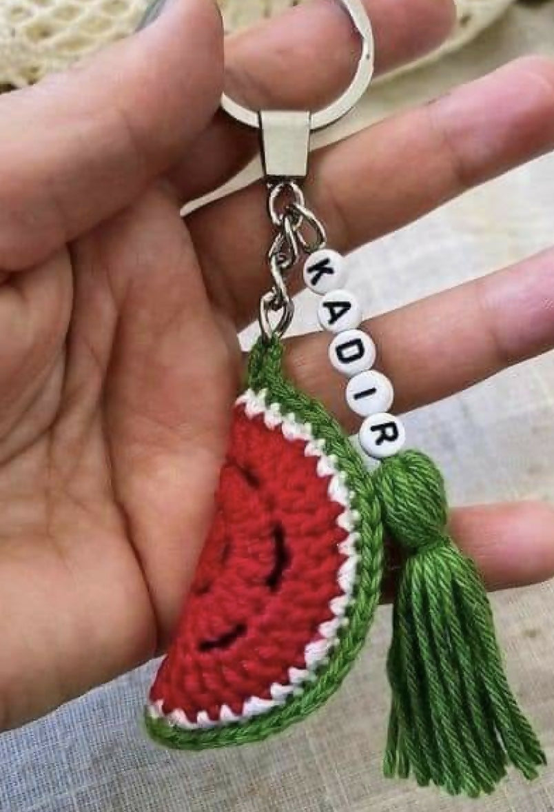 Hand holding a keychain with a watermelon design