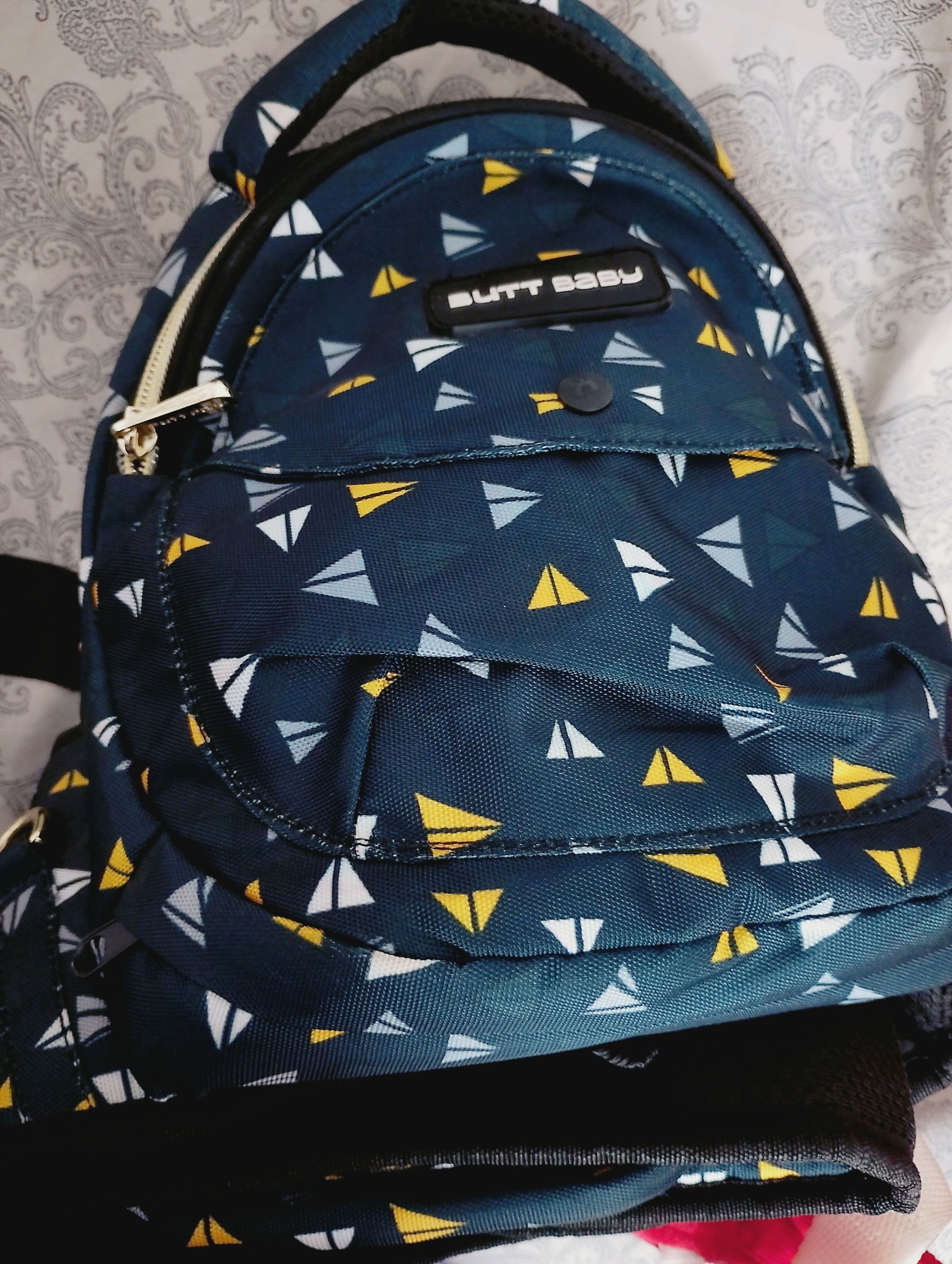 Navy blue backpack with yellow and white triangle pattern on a textured surface