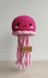 Pink crochet jellyfish toy with a visible brand tag on a light background