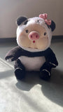 Plush toy resembling a panda with a pig's body on a light surface.