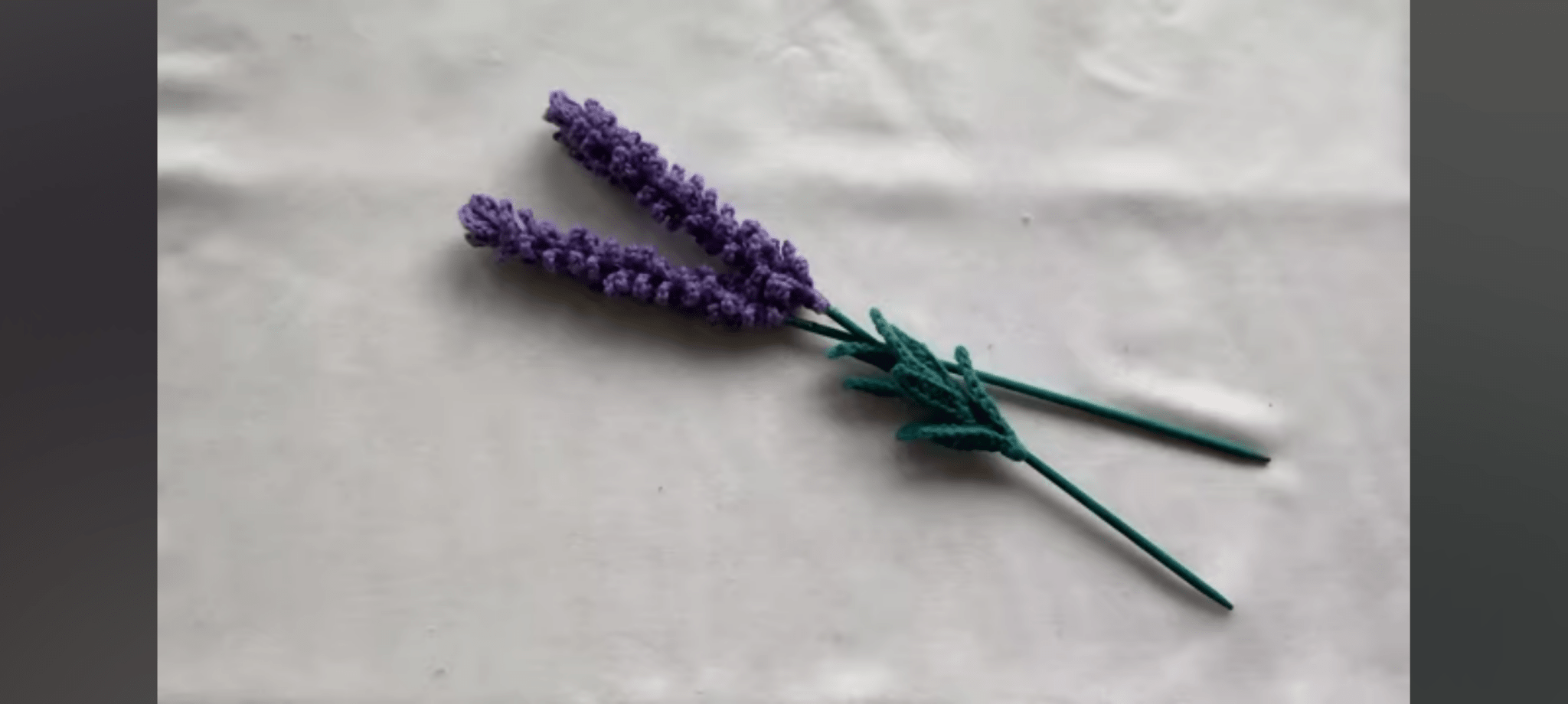 Two lavender flowers on a textured white surface