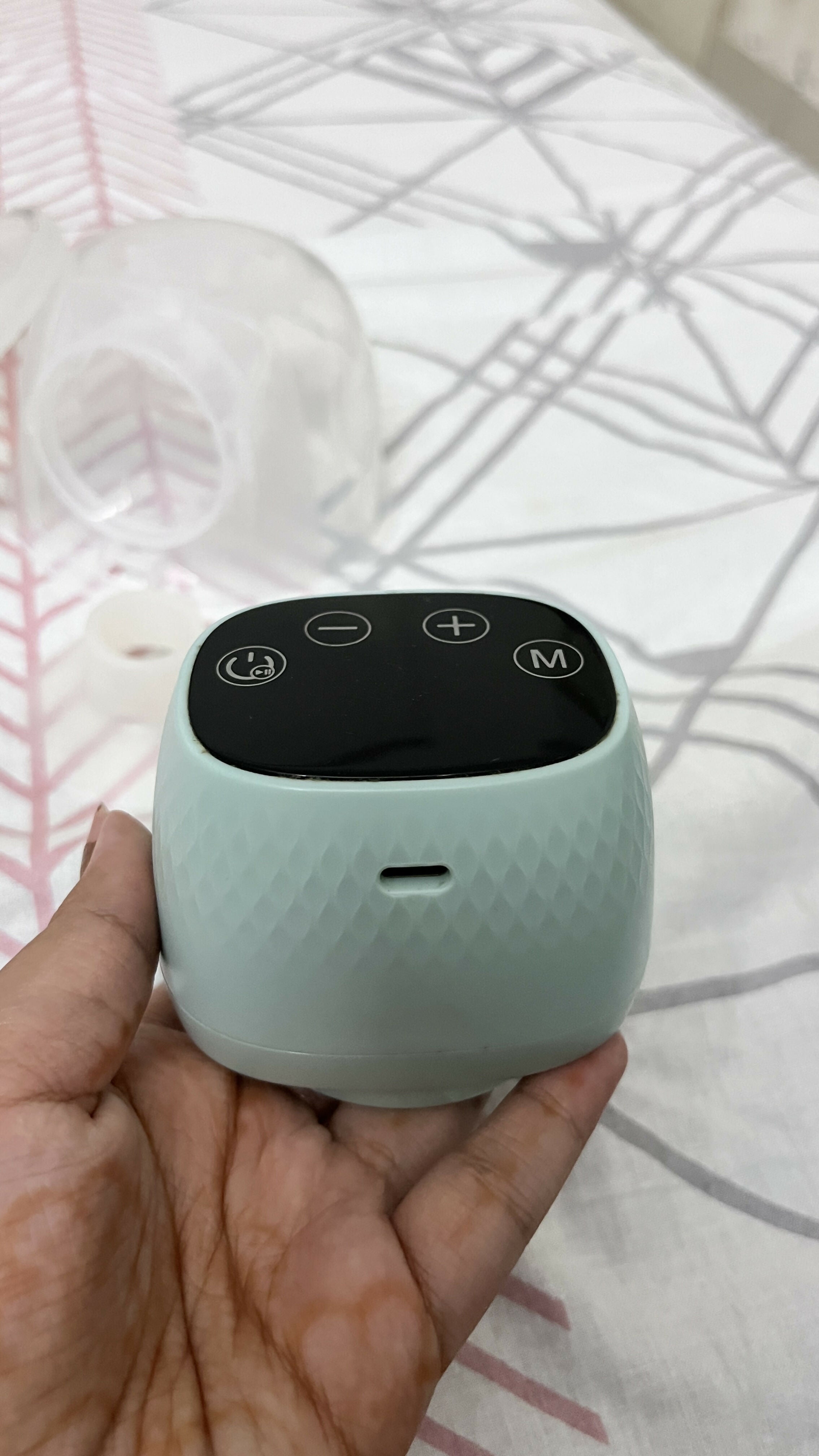 Small electronic device held in a hand on a patterned fabric background