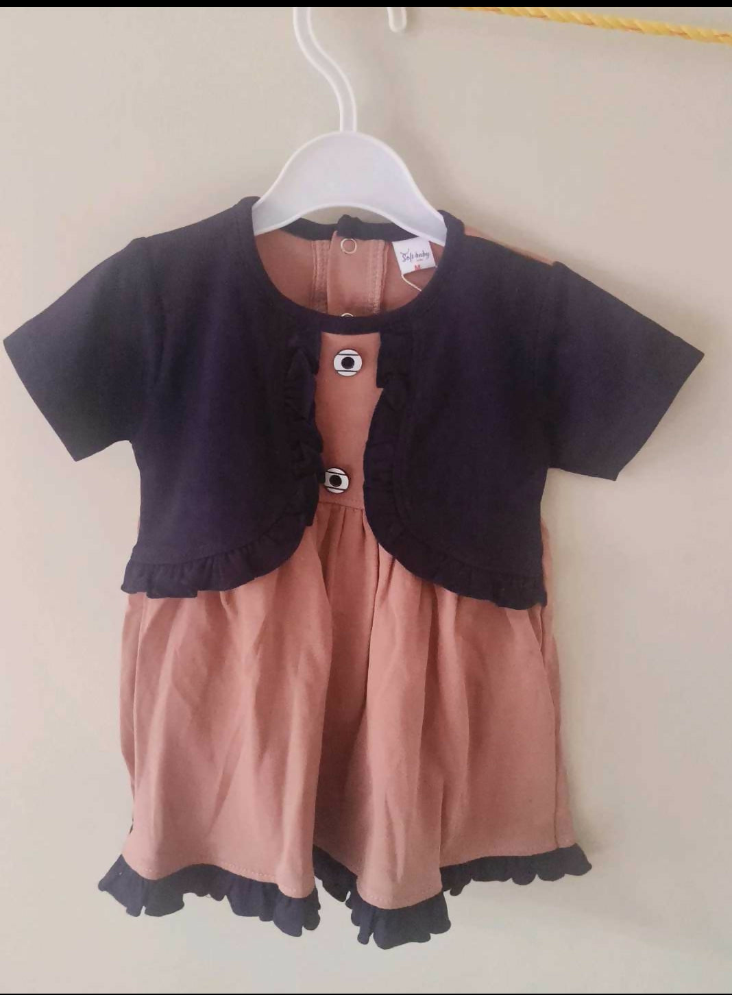 Children's outfit with black top and pink shorts on a hanger against a white background