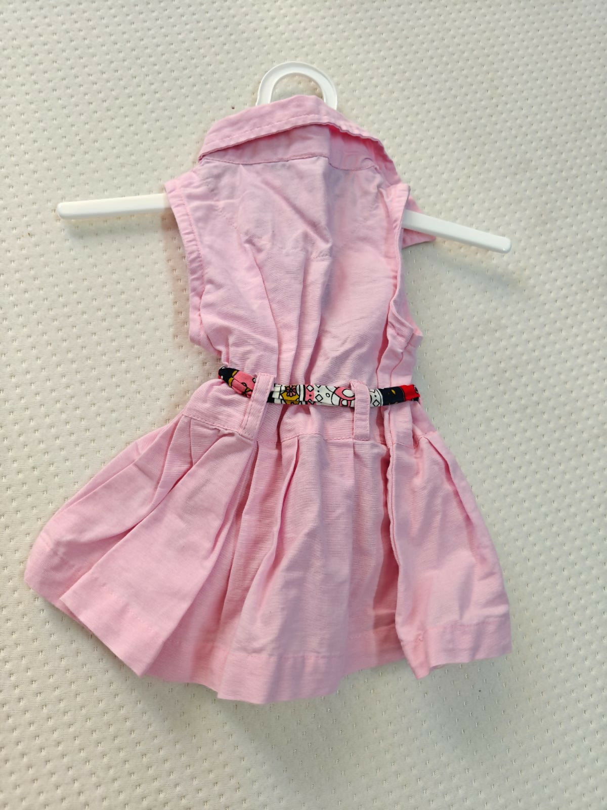 Pink dress on a hanger against a light gray background