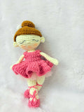 Crocheted doll with a pink dress and brown hat on a white background